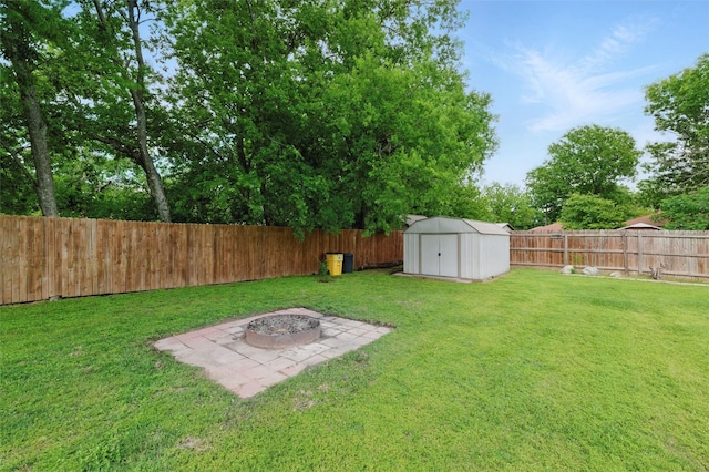 view of yard with a fenced backyard, a fire pit, an outbuilding, a patio, and a shed