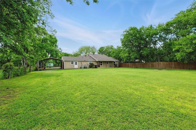 view of yard featuring fence and a carport