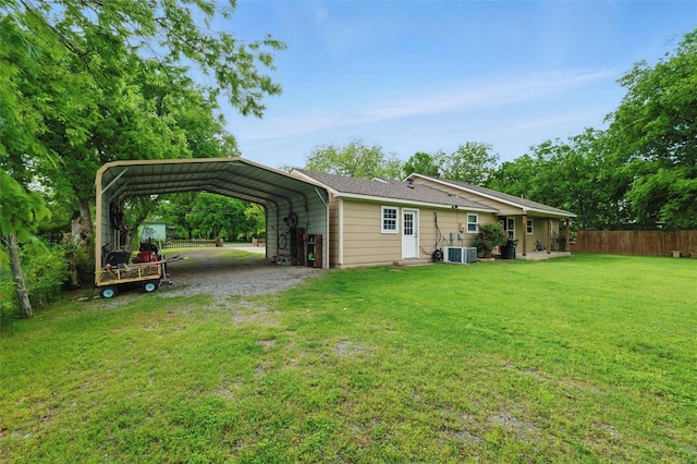 back of property with driveway, a detached carport, fence, a yard, and central AC