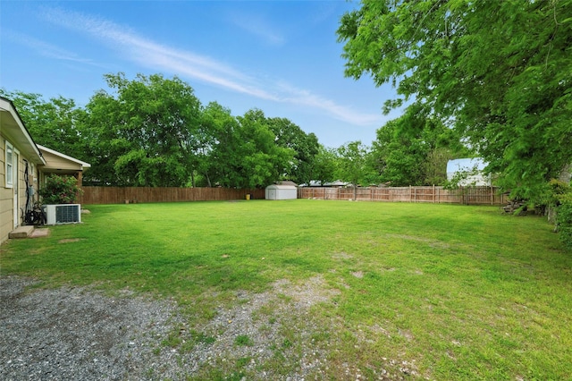 view of yard with a storage shed, central AC unit, an outbuilding, and a fenced backyard