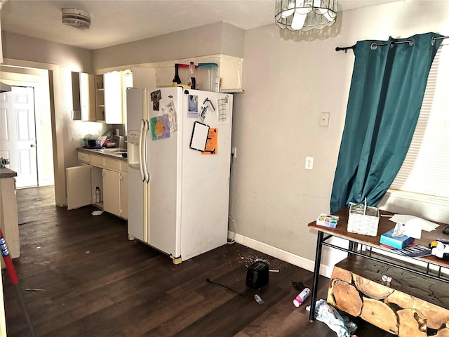 kitchen featuring dark wood-style flooring, white fridge with ice dispenser, and baseboards