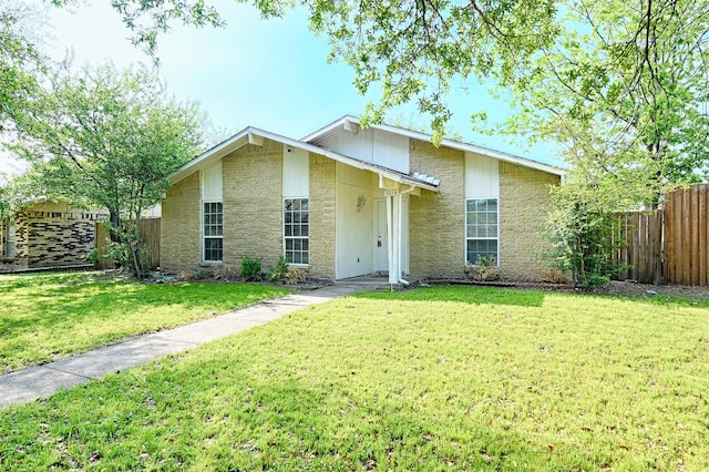 mid-century inspired home with a front yard, stone siding, and fence