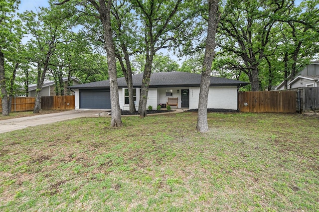 view of front of house with an attached garage, fence, a front yard, and concrete driveway