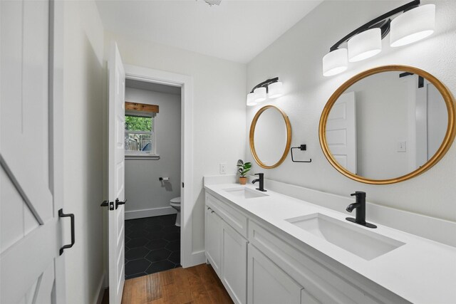 full bath featuring a sink, double vanity, and wood finished floors