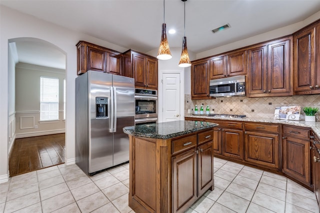 4465 Mira Vista Dr, Frisco, TX 75034 - kitchen featuring stainless steel appliances, arched walkways, dark stone countertops, and a kitchen island