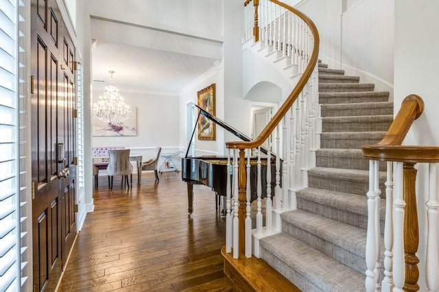 foyer featuring crown molding, a chandelier, stairway, and hardwood / wood-style flooring