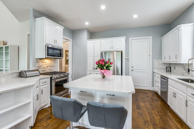 kitchen featuring decorative backsplash, white cabinetry, a sink, dark wood finished floors, and appliances with stainless steel finishes