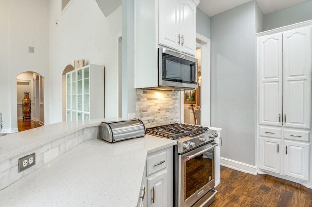 kitchen featuring light countertops, dark wood finished floors, stainless steel appliances, white cabinetry, and decorative backsplash