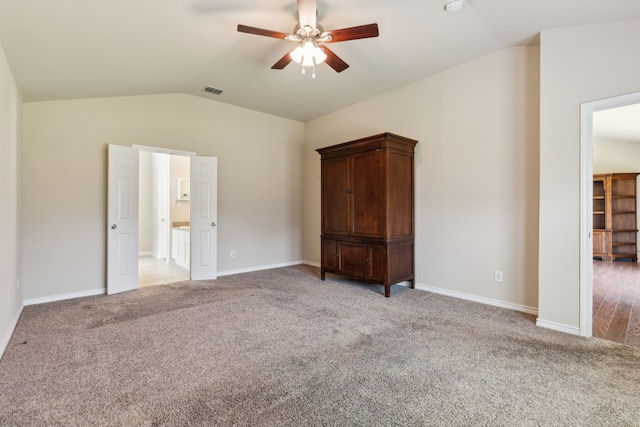 unfurnished bedroom featuring visible vents, vaulted ceiling, light carpet, and baseboards