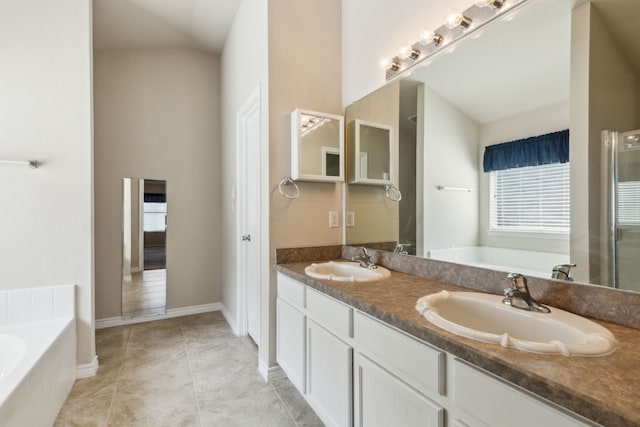 full bathroom featuring a garden tub, double vanity, a sink, and tile patterned flooring