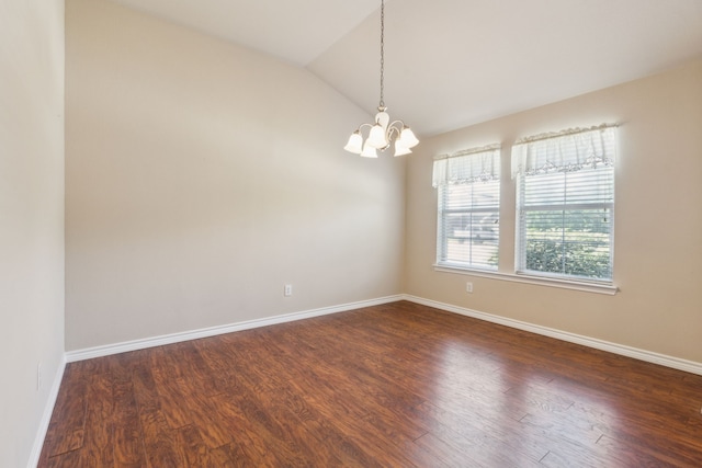 empty room featuring dark wood-style flooring, a notable chandelier, vaulted ceiling, and baseboards