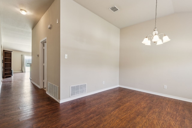 spare room with dark wood-style floors, visible vents, and an inviting chandelier