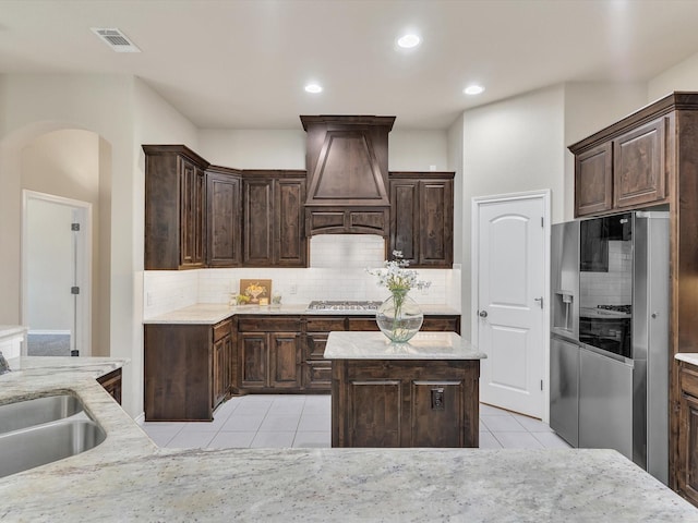 kitchen featuring light tile patterned floors, backsplash, custom exhaust hood, and stainless steel refrigerator with ice dispenser