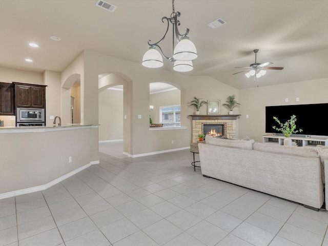 living room featuring arched walkways, ceiling fan, visible vents, and light tile patterned flooring