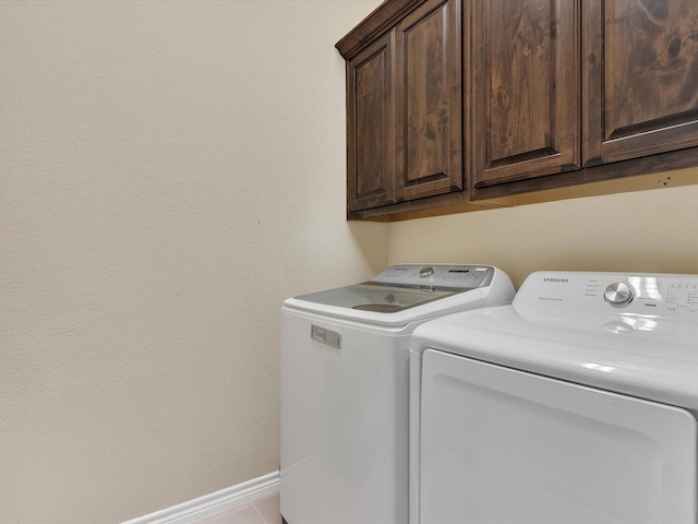 washroom with baseboards, cabinet space, and washing machine and clothes dryer