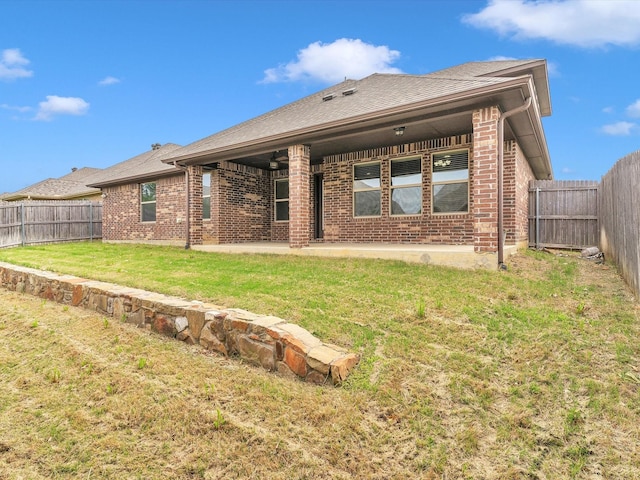 rear view of house featuring a lawn, brick siding, a fenced backyard, and a patio area