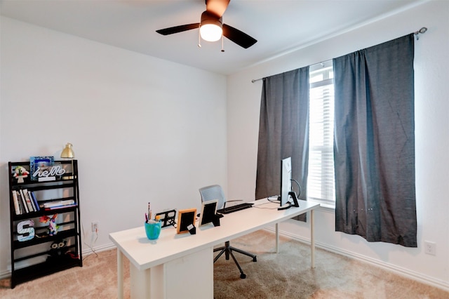 office space featuring baseboards, light carpet, a ceiling fan, and a wealth of natural light
