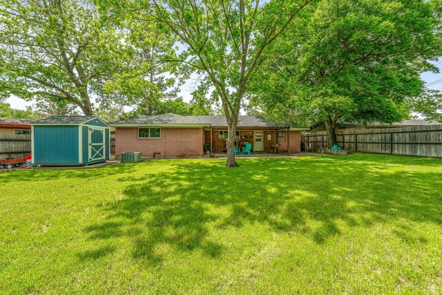 view of yard with a fenced backyard, a storage unit, an outdoor structure, and central AC unit