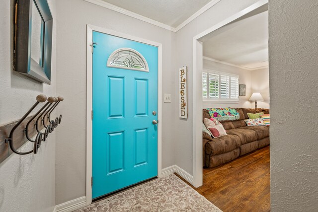 foyer entrance featuring baseboards, ornamental molding, and wood finished floors