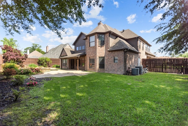 back of house featuring a lawn, brick siding, a fenced backyard, and a patio area