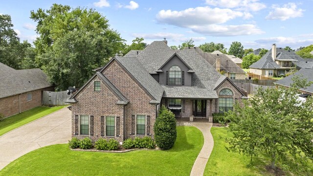 view of front of property with fence, a shingled roof, a front yard, and brick siding