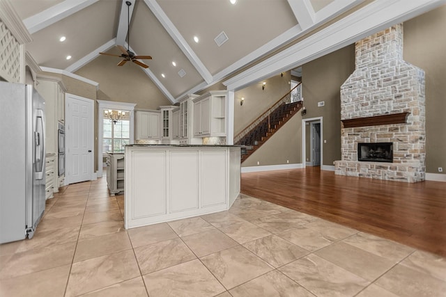 kitchen with appliances with stainless steel finishes, beam ceiling, high vaulted ceiling, ceiling fan with notable chandelier, and a peninsula