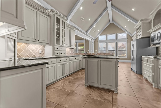 kitchen featuring gray cabinetry, backsplash, dark countertops, and beamed ceiling