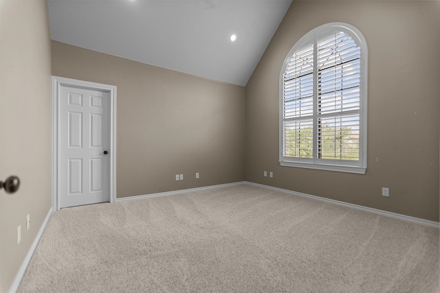 carpeted spare room featuring baseboards and lofted ceiling
