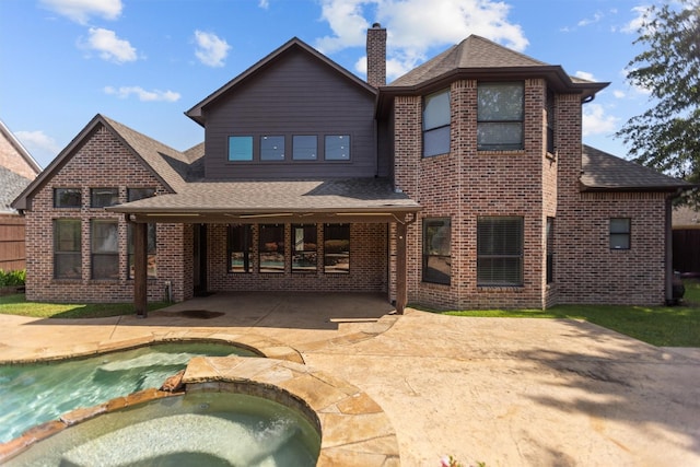 back of property featuring a shingled roof, a pool with connected hot tub, brick siding, a chimney, and a patio area