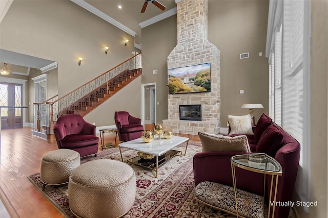 living area featuring crown molding, a high ceiling, stairs, a ceiling fan, and baseboards