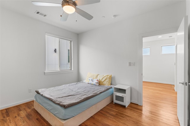 bedroom featuring wood finished floors, visible vents, a ceiling fan, and baseboards
