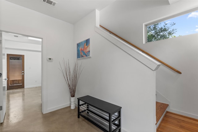 stairs with visible vents, finished concrete flooring, and baseboards