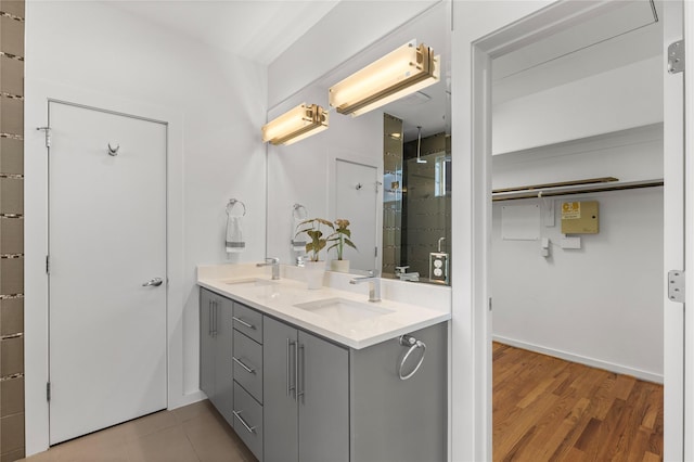 full bath with double vanity, wood finished floors, a stall shower, and a sink