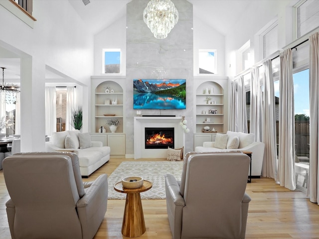 living area with high vaulted ceiling, a notable chandelier, light wood-type flooring, and a fireplace