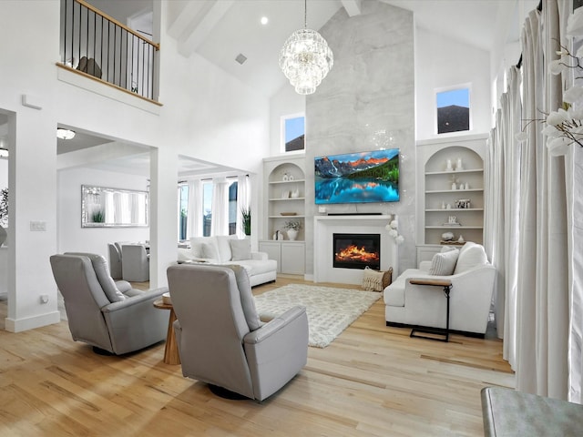 living area featuring high vaulted ceiling, a fireplace, wood finished floors, and a notable chandelier
