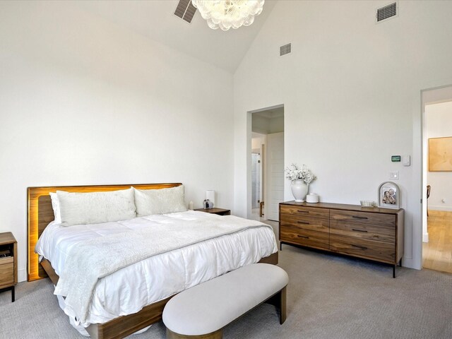 bedroom featuring high vaulted ceiling, visible vents, and light carpet