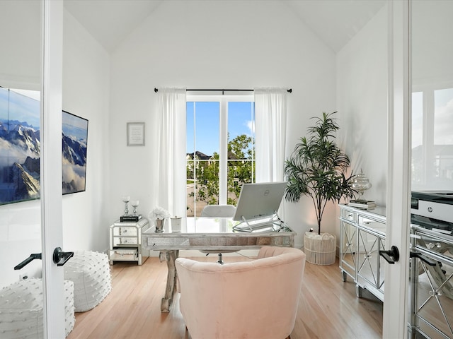 sitting room with light wood-style flooring and high vaulted ceiling