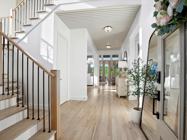 entrance foyer featuring stairs, french doors, baseboards, and light wood-style flooring