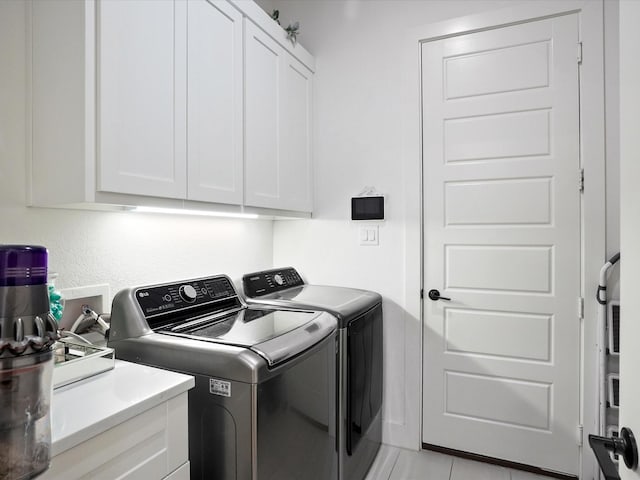 clothes washing area featuring separate washer and dryer and cabinet space