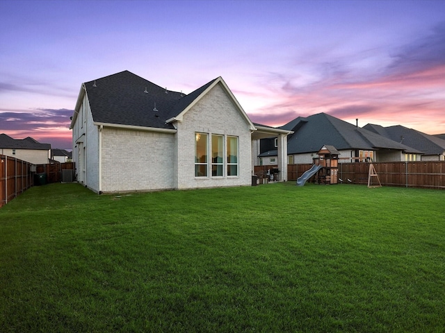 back of property with a lawn, a fenced backyard, and a playground
