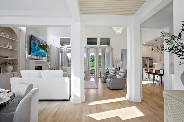 living area featuring an inviting chandelier, a fireplace, and light wood-type flooring