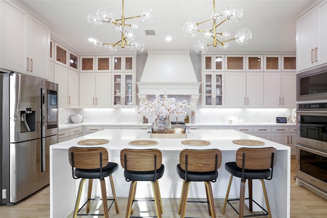 kitchen featuring custom range hood, a center island, a notable chandelier, and stainless steel appliances