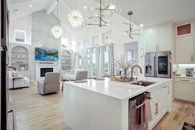 kitchen featuring high vaulted ceiling, light wood-type flooring, a chandelier, a sink, and appliances with stainless steel finishes