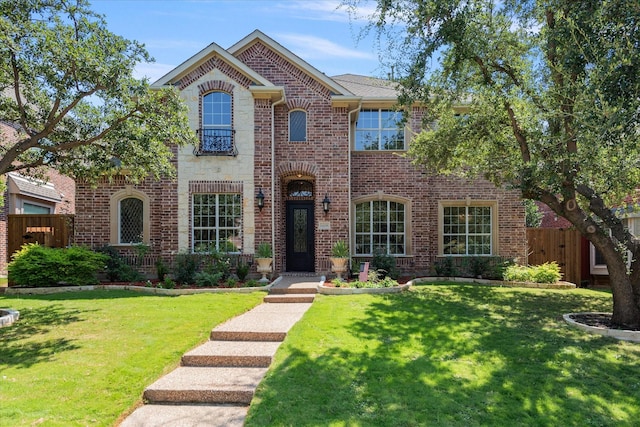 view of front facade featuring brick siding, fence, and a front yard