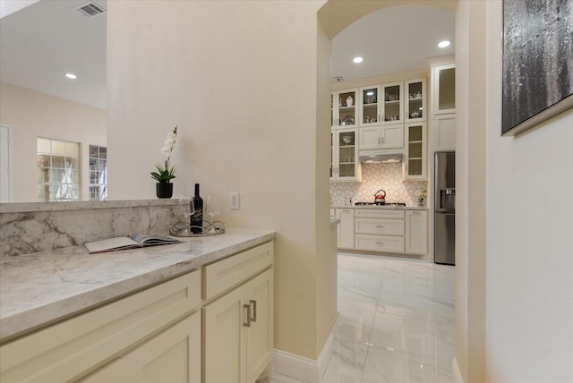 bar with tasteful backsplash, marble finish floor, recessed lighting, and stainless steel fridge