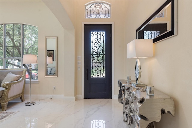 entryway featuring baseboards, arched walkways, a wealth of natural light, and marble finish floor