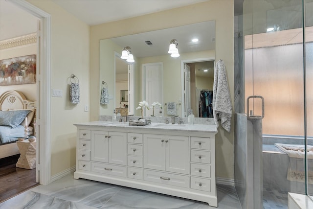 ensuite bathroom with double vanity, marble finish floor, a sink, baseboards, and a stall shower