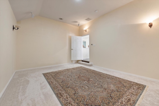 carpeted spare room featuring baseboards, visible vents, and vaulted ceiling