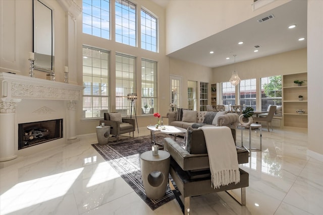 living room with recessed lighting, marble finish floor, a high end fireplace, visible vents, and a towering ceiling