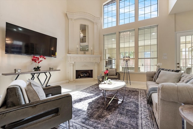 living area featuring baseboards, a high ceiling, a fireplace, and marble finish floor